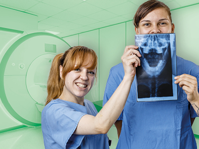 Zwei medizinische Fachkräfte in blauen Kitteln stehen in einer Klinik. Eine Person hält ein Röntgenbild eines Kiefers hoch, beide lächeln. Das Bild vermittelt den Kontext von Radiologie und Diagnostik.