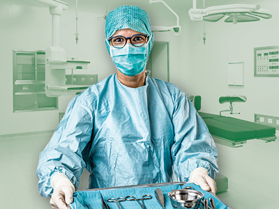 Medizinische Fachkraft im Operationssaal, steril bekleidet mit Haube, Maske und Handschuhen, hält ein Tablett mit chirurgischen Instrumenten. Im Hintergrund ein leerer OP.